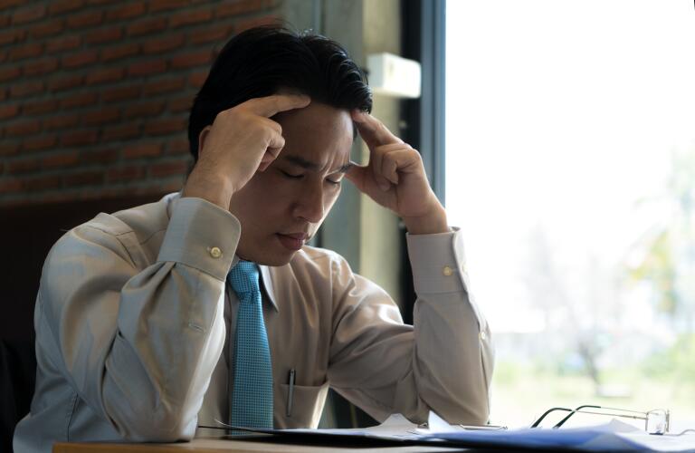 frustrated businessman sitting in cafe with hands on head