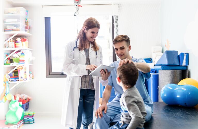 Young Caucasian father and young son with female doctor in play therapy room