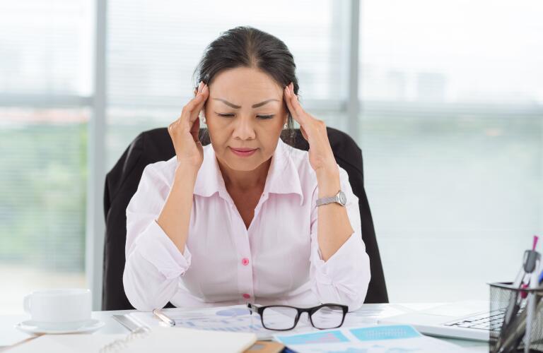 tired senior woman sitting at office desk