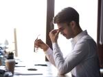 tired business man at computer taking off glasses and rubbing eyes