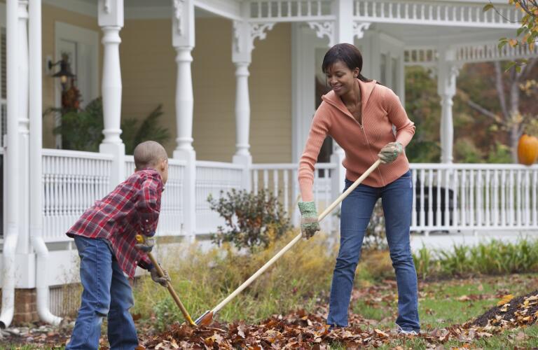 Black mother and son raking leaves