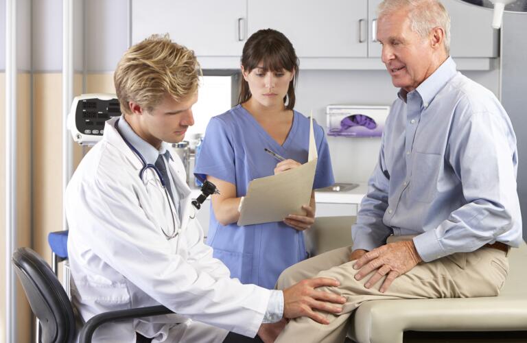 Doctor Examining Male Patient With Knee Pain