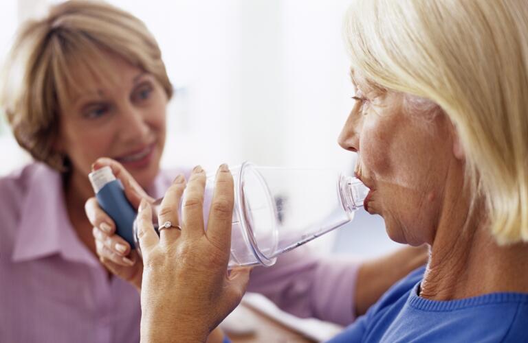 woman using asthma spacer with inhaler