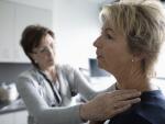 female doctor examining female patient's neck and shoulder 