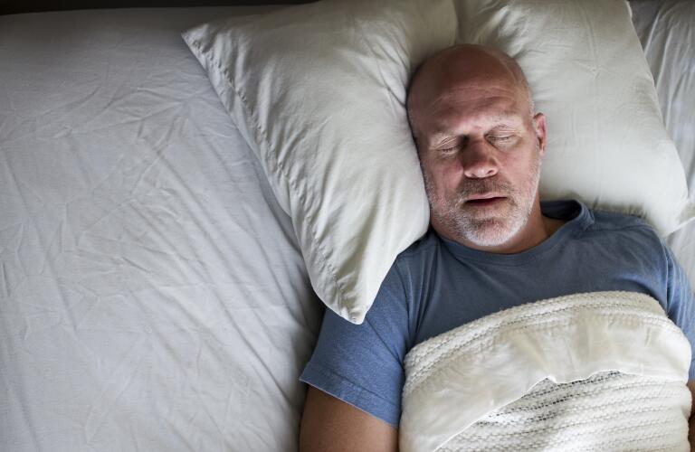 senior man sleeping on bed in bed
