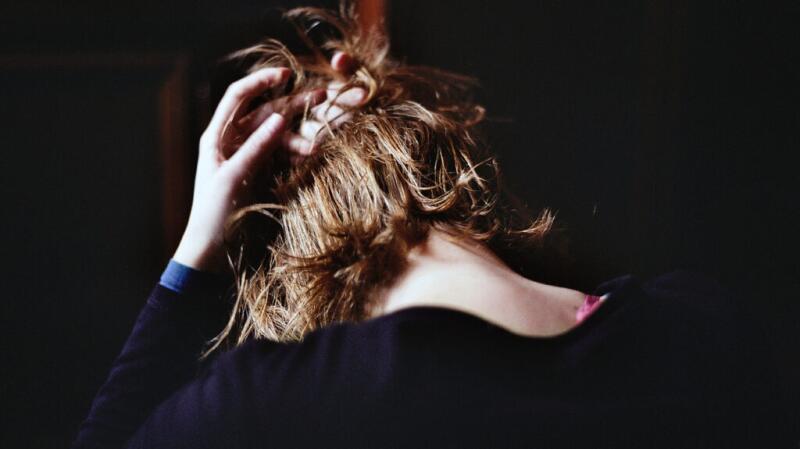 A woman with short hair is bending her neck downward