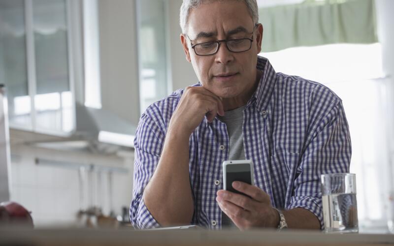 Middle aged man with glasses looking at smartphone