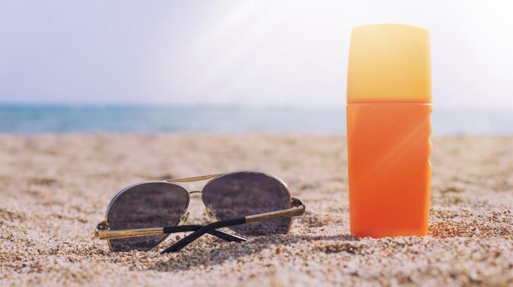 sunscreen-bottle-with-sunglasses-on-beach