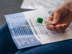 unidentifiable woman holding sterile swab and tube as she read instructions for her coronavirus home test for COVID-19