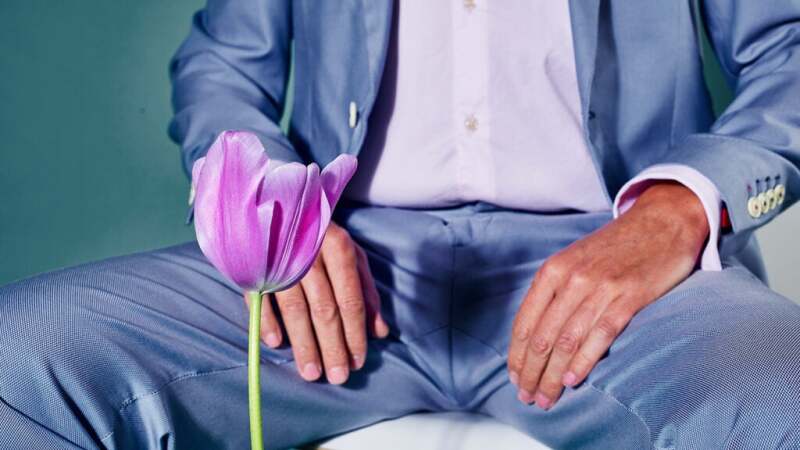 Image of a male's lap with a pink tulip in the forefront