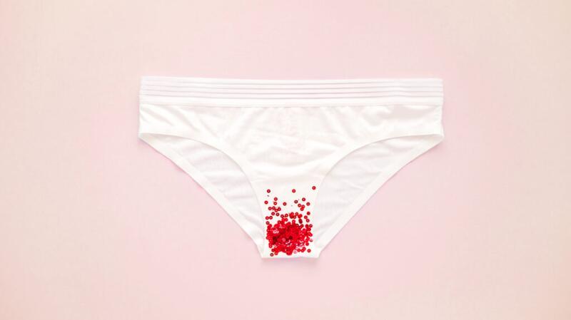 Photo concept of white underwear with red sequins to represent vaginal bleeding