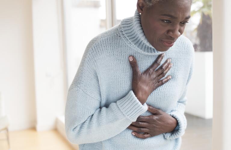 Senior woman holding stomach and chest in discomfort