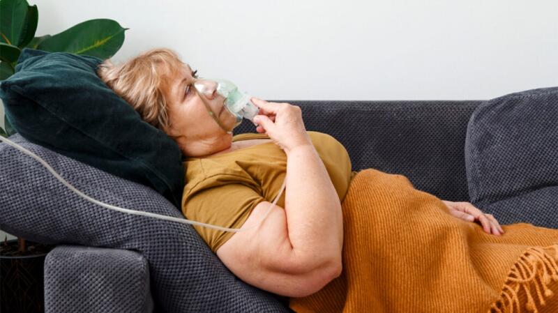 female laying on couch with oxygen mask