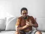 Man sitting on couch with chest pains 