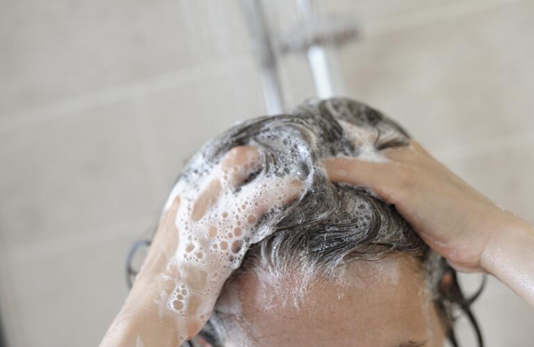 Unseen Caucasian woman shampooing hair in shower
