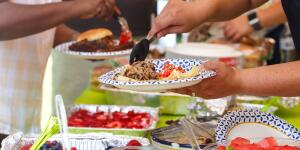 Foods to Avoid When You Have Cancer and more people helping themselves to food at outdoor potluck party