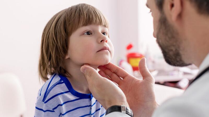 A child gets their throat checked by a doctor