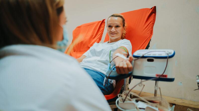 a woman is smiling while giving a blood sample