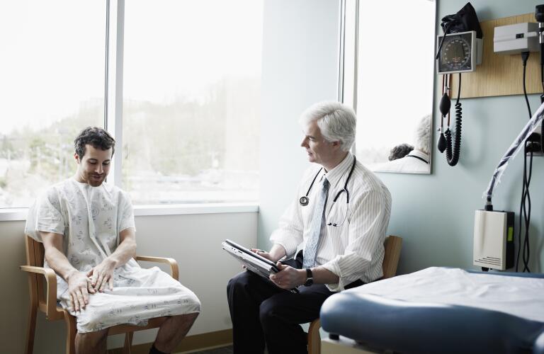 Male doctor in discussion with male patient in exam room