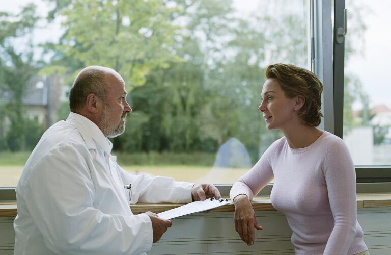 Male doctor sitting with female patient by window, side view