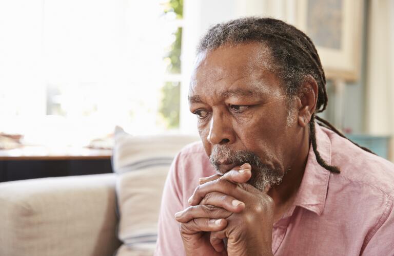 serious senior african american man sitting on couch