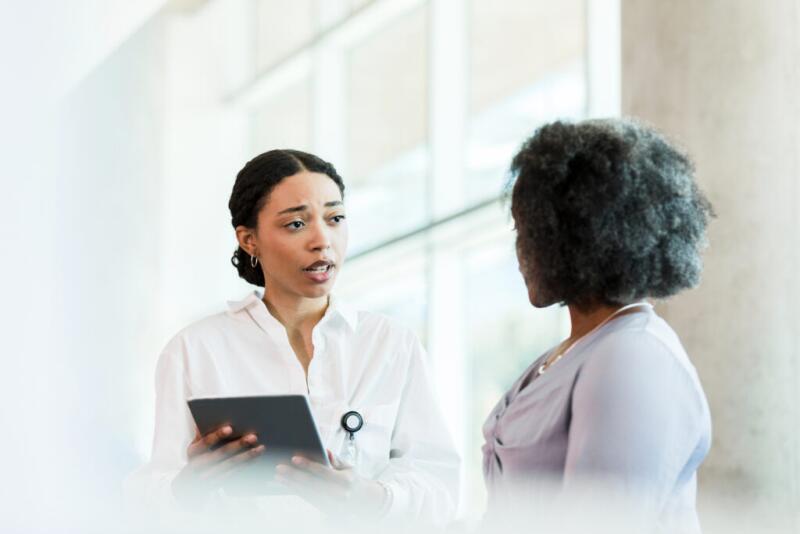 Female doctor holds electronic medical record while talking to patient