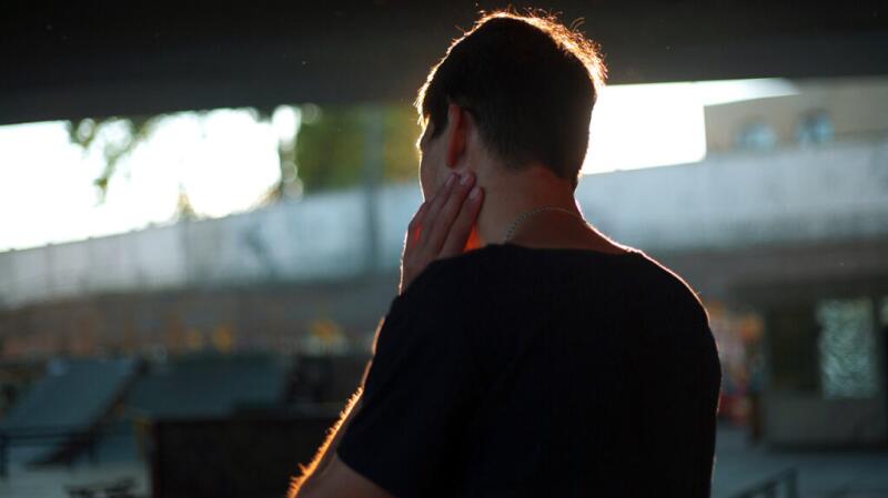 Male with his hand on his jaw, facing away