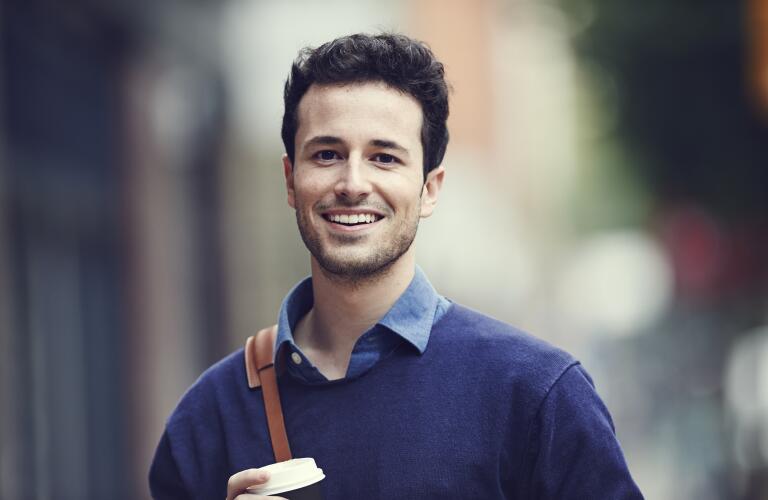 portrait-of-smiling-young-man-carrying-bag
