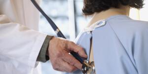 Close-up of doctor using stethoscope on woman's back to listen to lungs and breathing