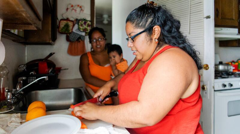 A woman chopping up food with her family