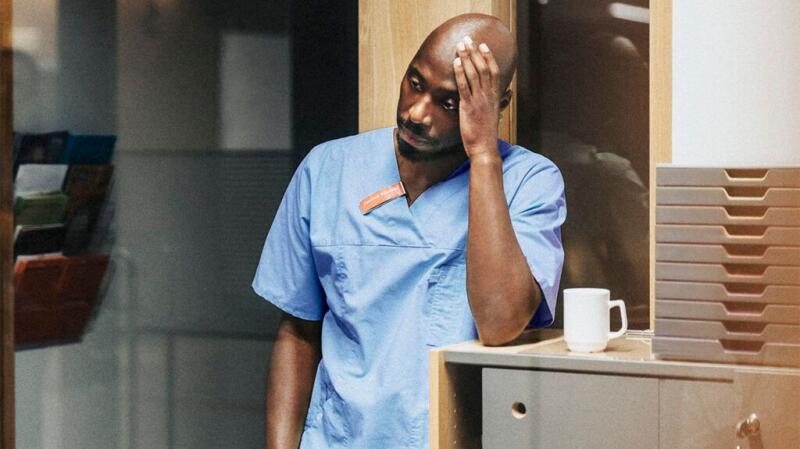 A healthcare professional with one hand on their head.