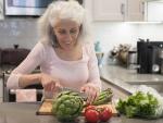 Senior woman cutting fresh vegetables