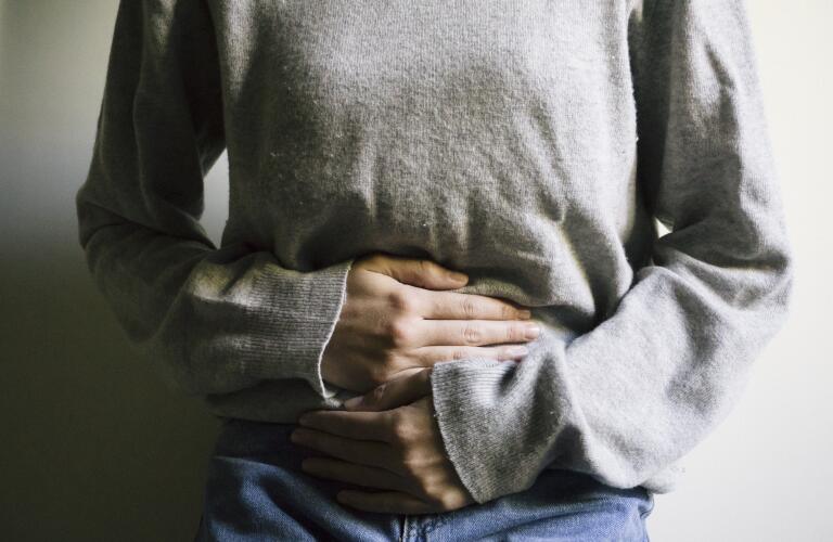 Cropped photo of young female Caucasian woman holding stomach in pain