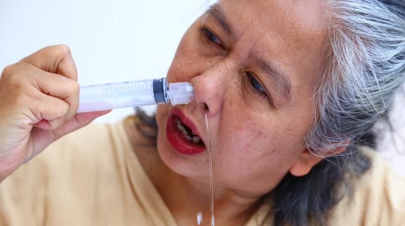 Asian elderly woman washes out the nose with saline