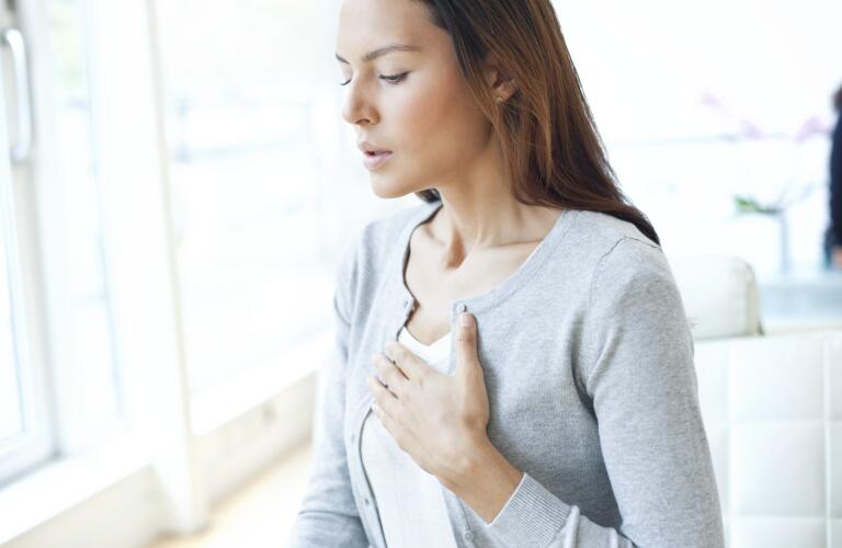 young woman with hand on chest and concern on face and trouble breathing