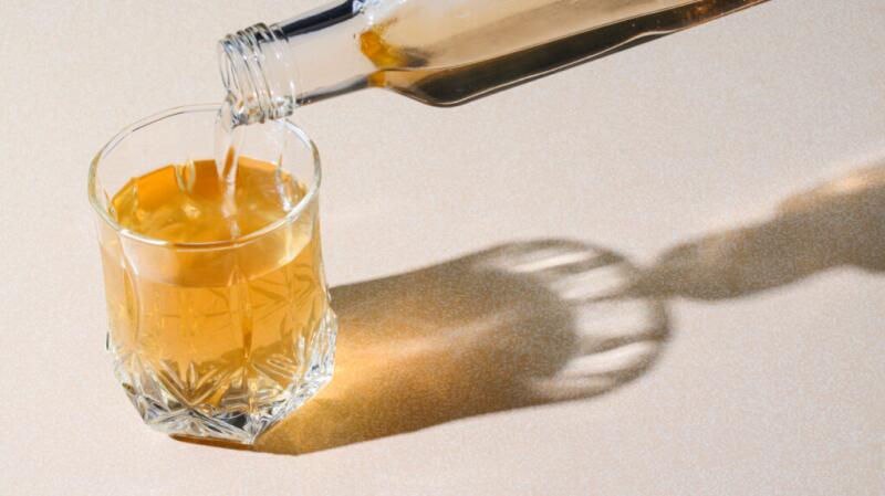 A glass being filled with apple cider vinegar from a glass bottle