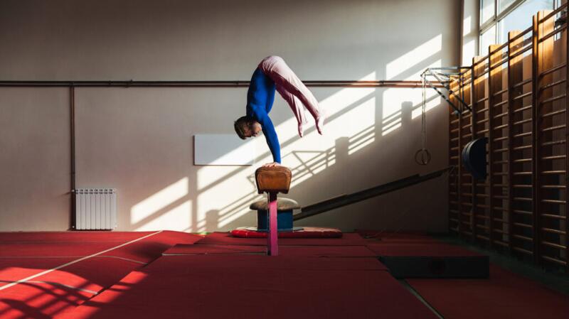 Gymnast doing handstand on balance beam