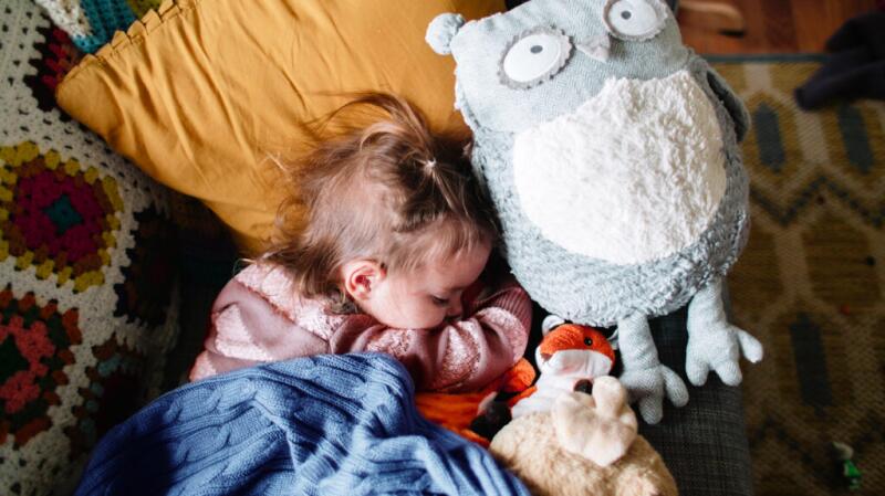 child sleeping on couch with stuffed animals