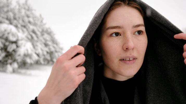 a woman is in a snowy field wearing a hood