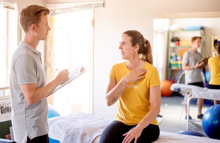 woman talking about her shoulder with a physical therapist in his office