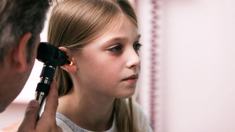 young female getting ear exam with otoscope