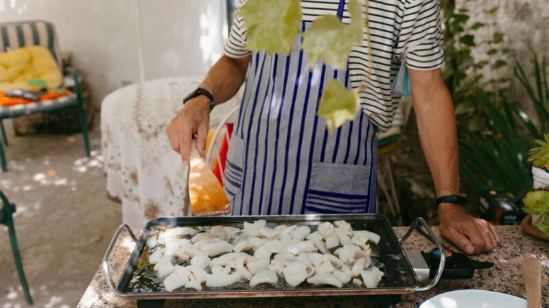 A man is cooking fresh fish as part of a healthy gallbladder diet. Try to avoid frying when possible.