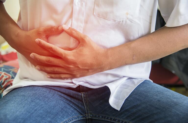 man with abdominal pain clutching stomach with hands