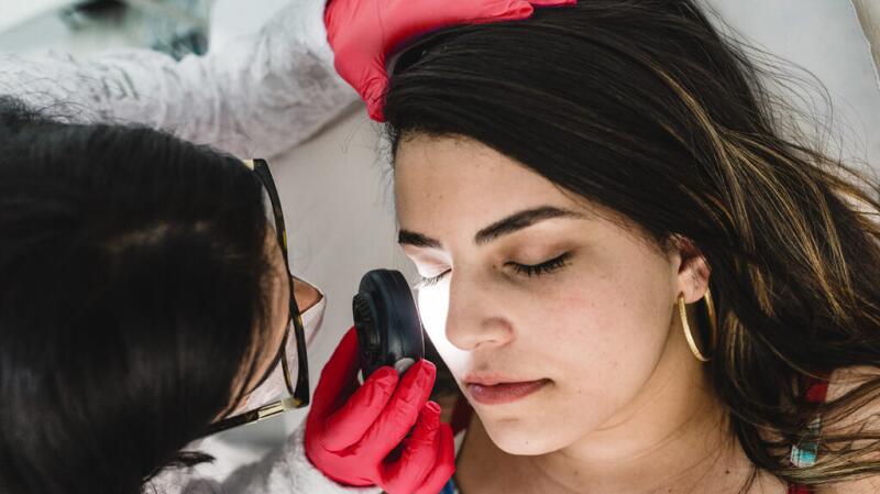 Doctor performing a skin check on a person's face