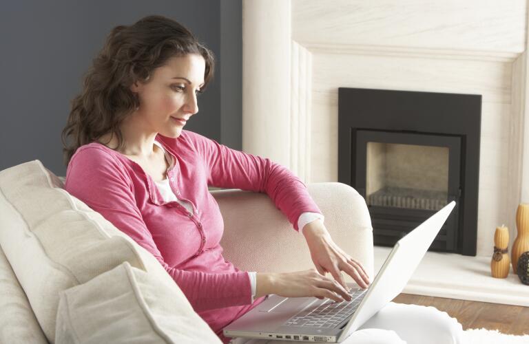 Woman Using Laptop Relaxing Sitting On Sofa At Home