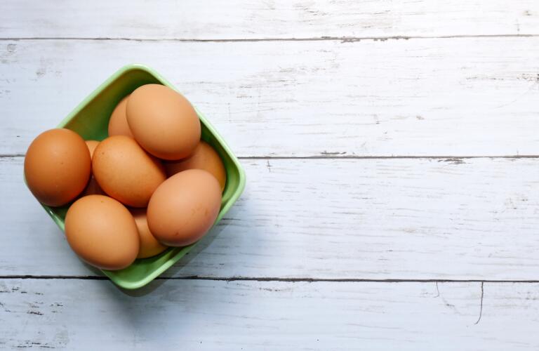 Overhead view of brown-shell eggs in green container