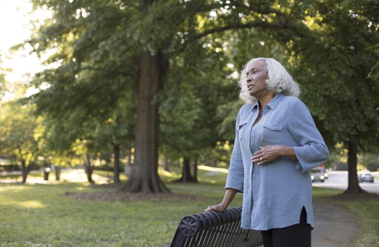 Senior African American woman in park with hand on stomach