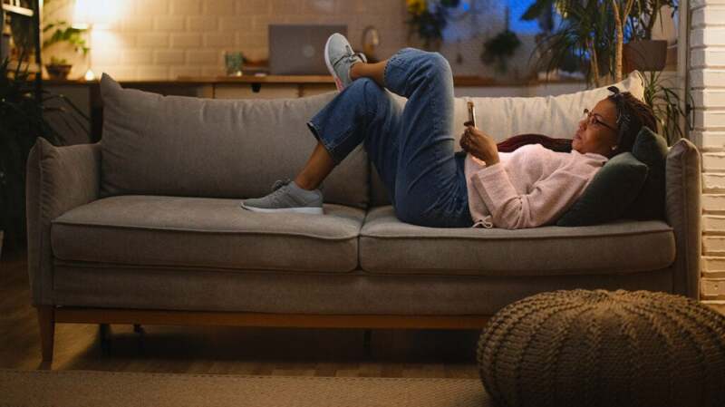 a woman with Crohn's disease is lying on a sofa researching symptoms
