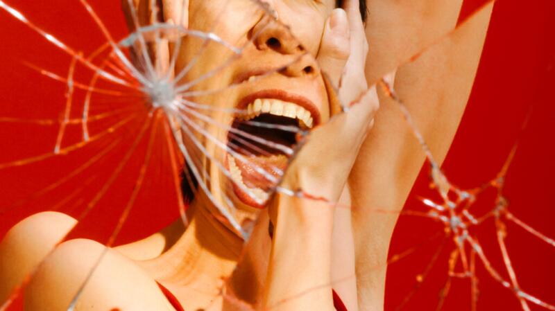 A person's screaming reflection in a shattered mirror