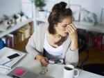 Young Caucasian woman at desk with headache or migraine or fatigue
